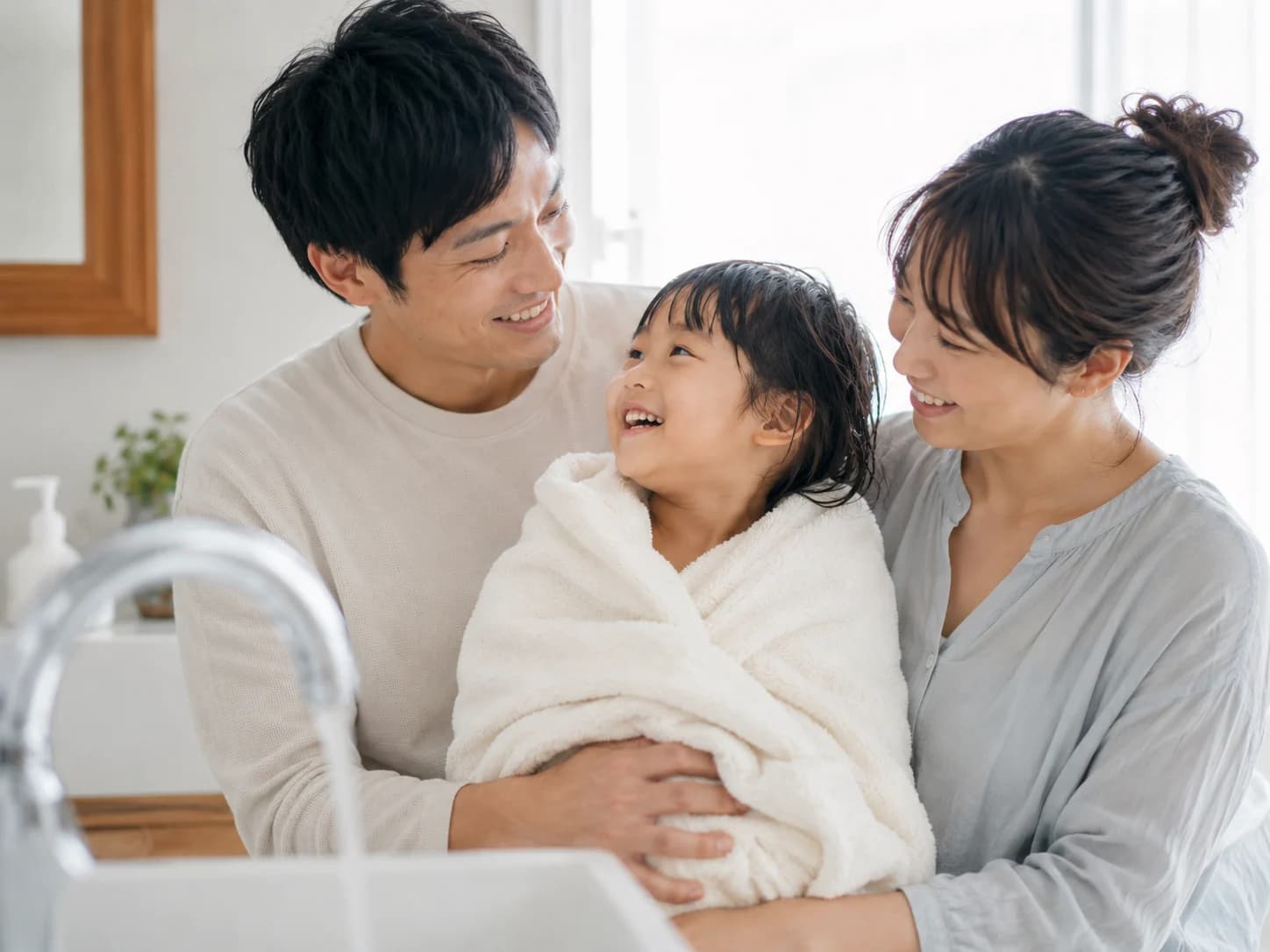 お風呂上がりに笑顔のお子さんを家族で見守るシーン